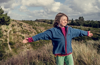 barn står med armene i vejret og nyder vinden i naturen